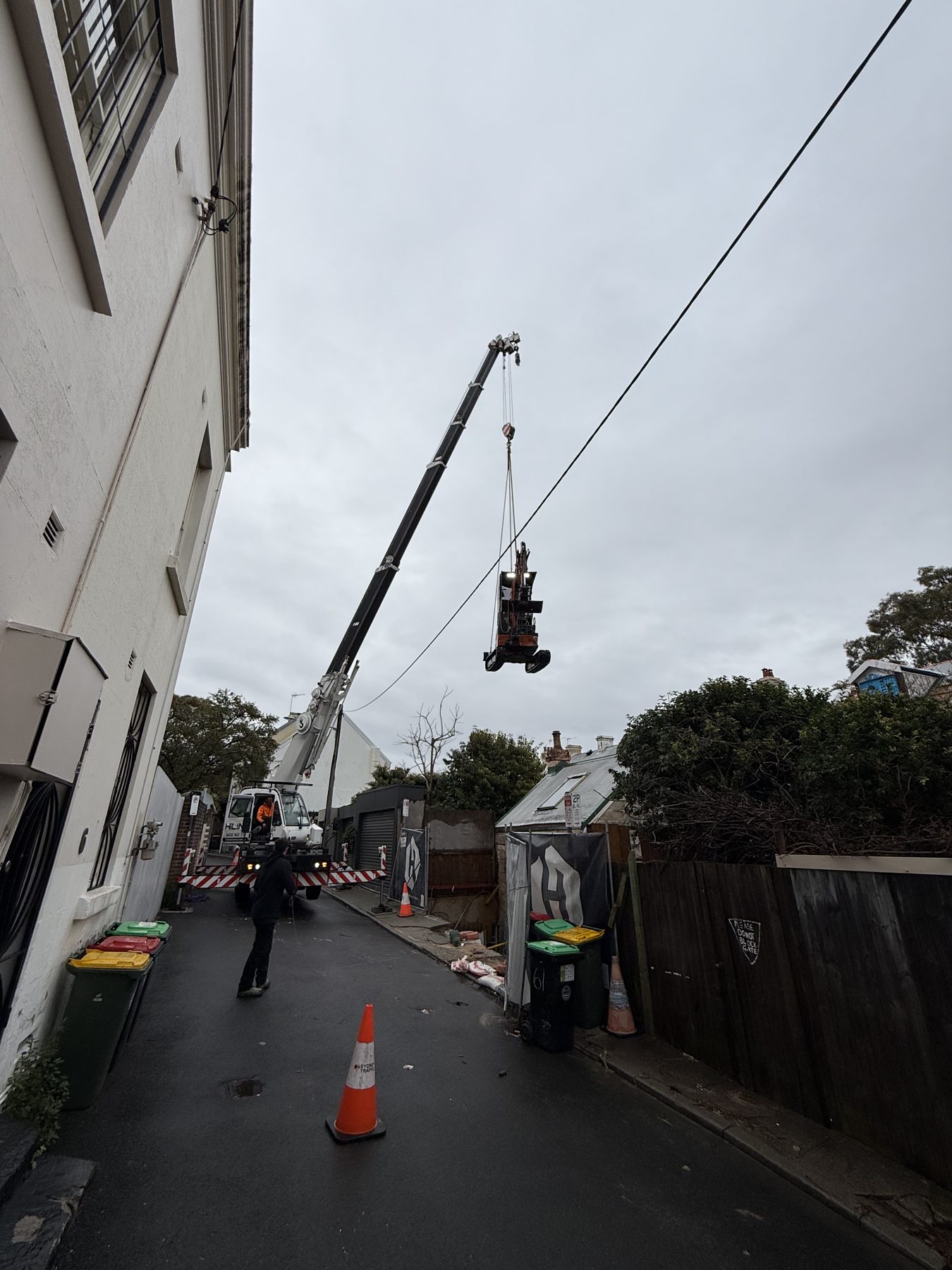 Franna crane lifting a mini excavator out of a Paddington back lane site